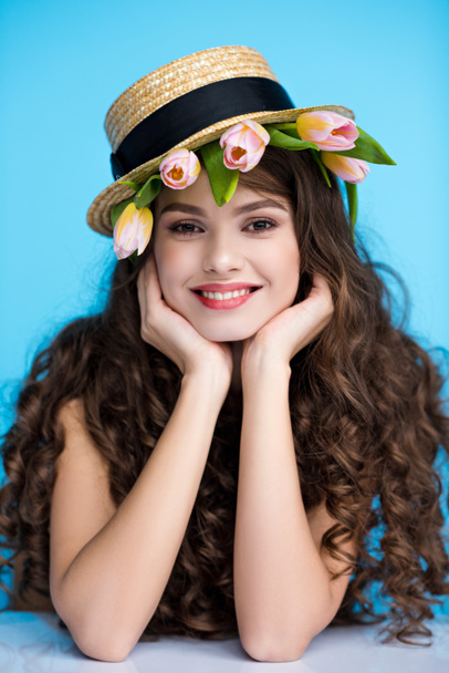 jeune femme souriante en chapeau canotier avec des tulipes fraîches sous elle
 - Photo, image