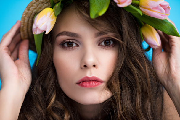 young woman in canotier hat with beautiful tulips under it looking at camera - Foto, Imagem