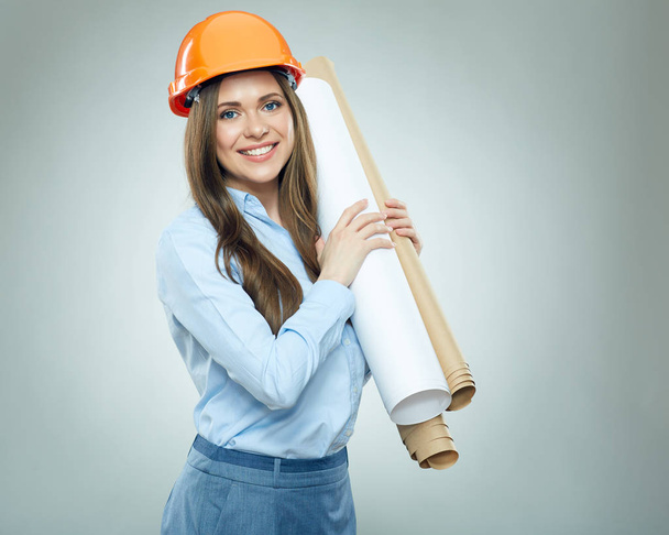 portrait de femme ingénieure souriante en casque de protection orange et chemise bleue tenant un plan en papier
  - Photo, image