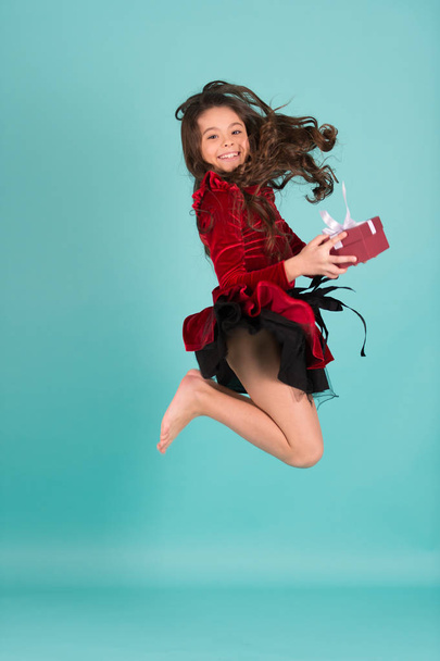 Happy child in red dress with present box jump barefoot - Фото, зображення