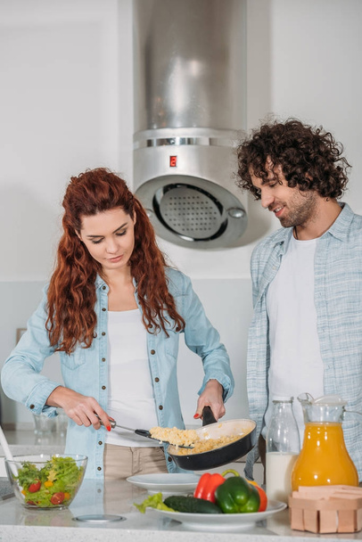 girlfriend putting omelet on plate and boyfriend looking at food - Φωτογραφία, εικόνα