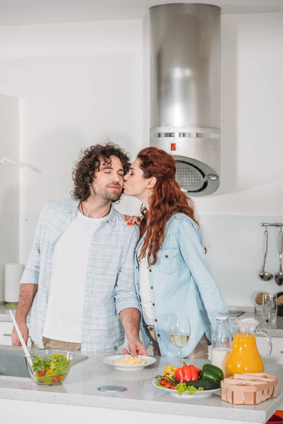 girlfriend kissing happy boyfriend at kitchen - Foto, Bild