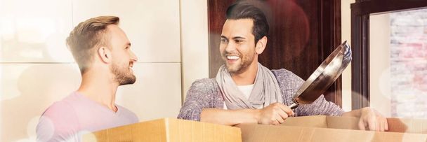 Gay couple unpacking cardboard boxes at home - Photo, image
