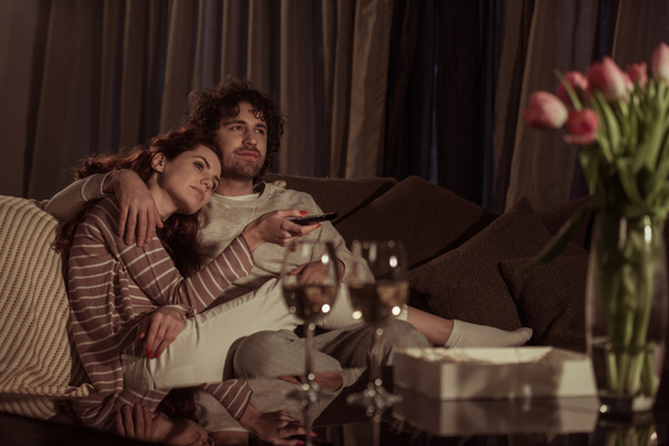 heterosexual couple watching tv on sofa in evening  - Fotografie, Obrázek