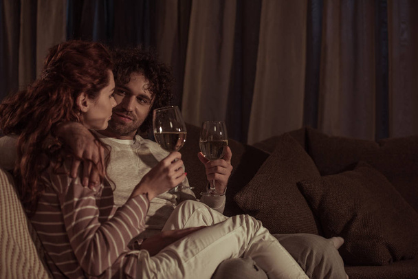pari istuu sohvalla lasilliset samppanjaa illalla
 - Valokuva, kuva