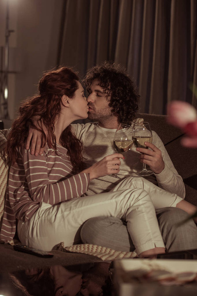 heterosexual couple kissing on sofa in evening - Fotó, kép