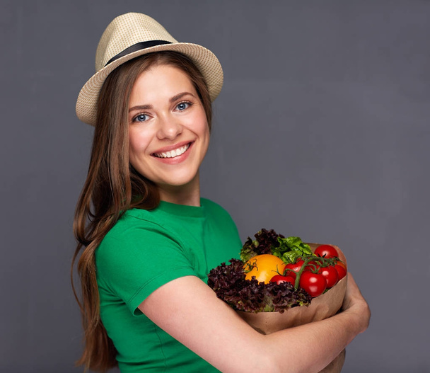 woman holding paper bag with summer vegetables. - Фото, изображение