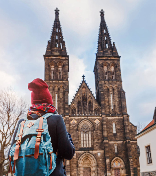 Pretty young female tourist with backpack looking at majestic Basilica of St. Peter and Paul in Prague - Photo, Image