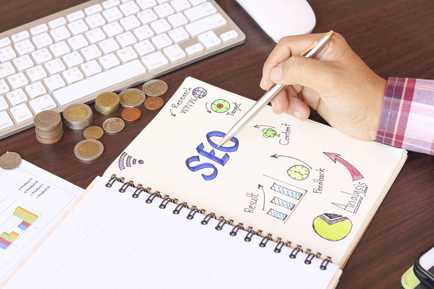 Escritura a mano Vista superior de SEO y papel gráfico en cuaderno con lupa, moneda de dinero en mesa de trabajo
 - Foto, Imagen