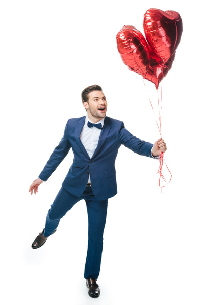 happy young man with heart shaped balloons isolated on white - Foto, afbeelding