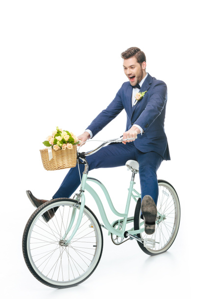 noivo feliz em terno andar de bicicleta retro com buquê de casamento na cesta isolada no branco
 - Foto, Imagem