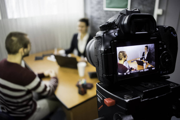 камера на съёмках деловой встречи между мужчиной и женщиной
 - Фото, изображение