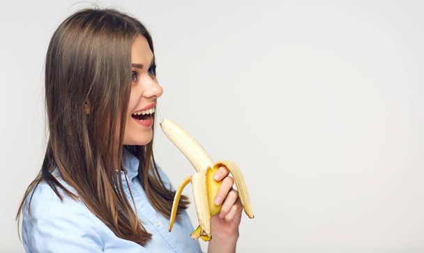 Smiling woman eating peeled banana. - Fotó, kép