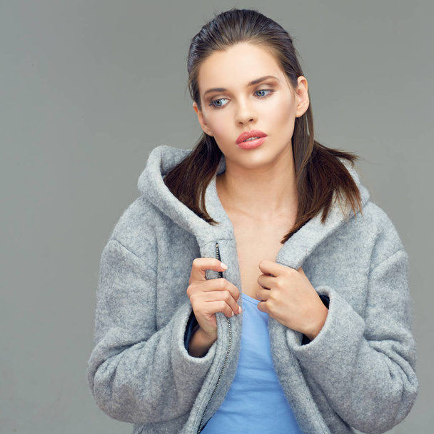 beautiful female fashion model wearing gray coat with deep hood posing on gray background - Photo, Image