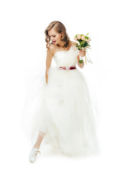 smiling bride in beautiful wedding dress with flowers in hand isolated on white - Fotó, kép
