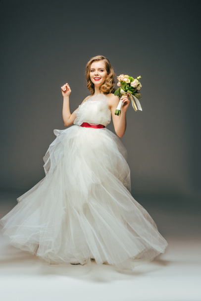 smiling bride in beautiful wedding dress with flowers in hand - Foto, Bild