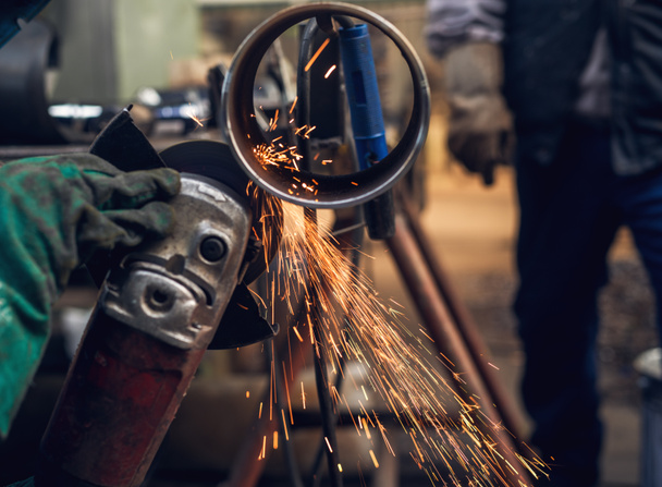 profesjonalny pracownik w metalowej rury ochronne jednolite cięcie z Szlifierki elektryczne w warsztaty przemysłowe - Zdjęcie, obraz