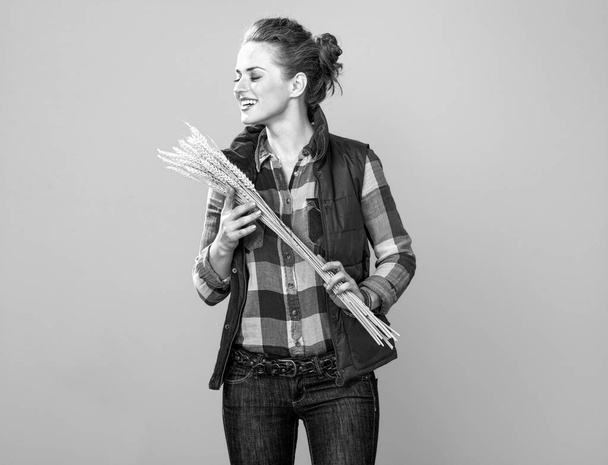 Portret szczęśliwy kobieta młody rolnik w kraciaste koszule, ciesząc się silnie pszenicy - Zdjęcie, obraz