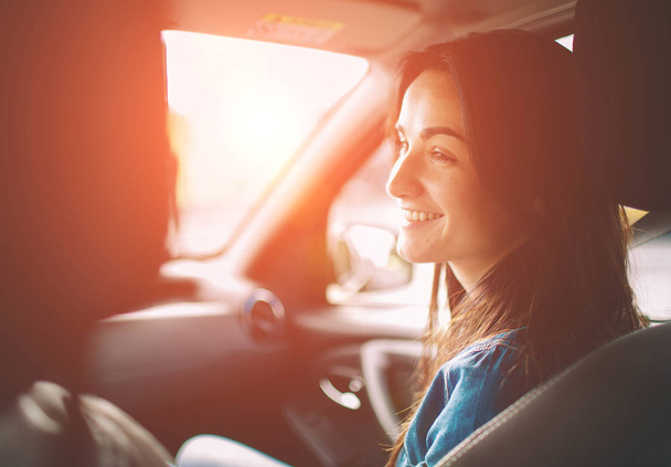Beautiful woman smiling while sitting on the front passenger seats in the car - Foto, imagen
