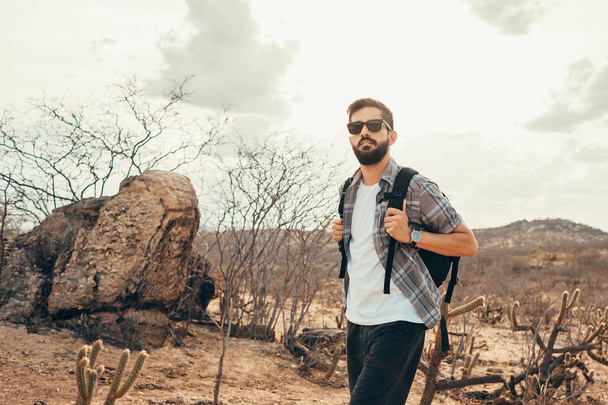 Man traveling with backpack hiking in desert. Travel lifestyle success concept - 写真・画像