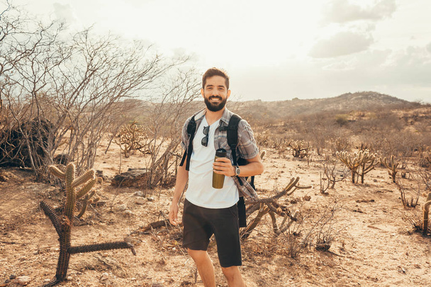 Man traveling with backpack hiking in desert. Travel lifestyle success concept - Photo, image