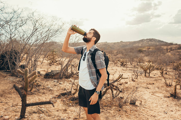 Tired hiker drinks water from a bottle - Foto, Bild