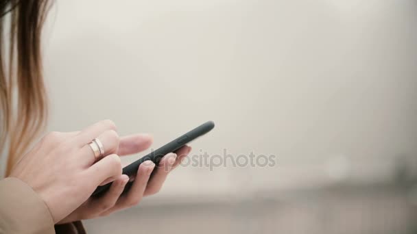 Zblízka pohled na ženské ruce držící mobilní telefon s dotykovým displejem. Žena používající smartphone v mlhavé parku. - Záběry, video