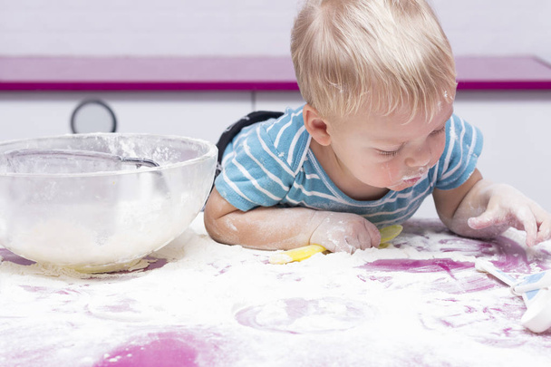 Funny toddler on the kitchen playing with flour. - Valokuva, kuva