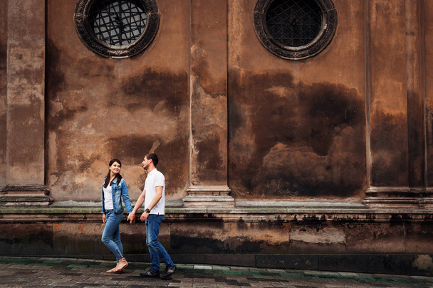 een wandeling van twee jonge mensen die houden van de handen in de buurt van een oud gebouw w - Foto, afbeelding