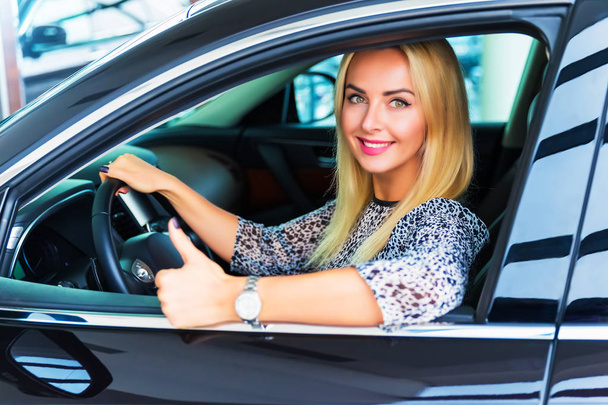 Ευτυχισμένη γυναίκα οδηγός δείχνει τους αντίχειρες επάνω στο αυτοκίνητό της - Φωτογραφία, εικόνα