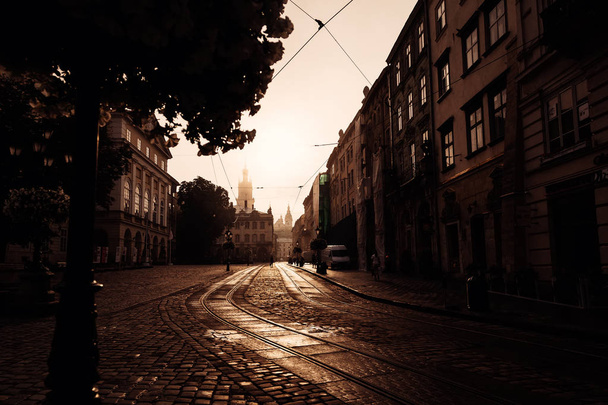 alte Straße mit einem Bürgersteig und Sonnenaufgang über einer schönen Stadt lvi - Foto, Bild