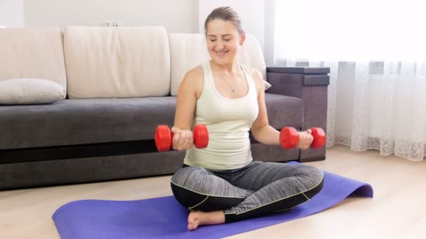güzel genç kadın fitness mat evde dumbbells ile egzersiz 4 k görüntüleri - Video, Çekim