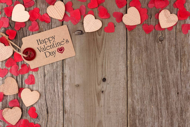 Happy Valentines Day gift tag with scattered wooden hearts and confetti corner border on a rustic wood background - Photo, Image