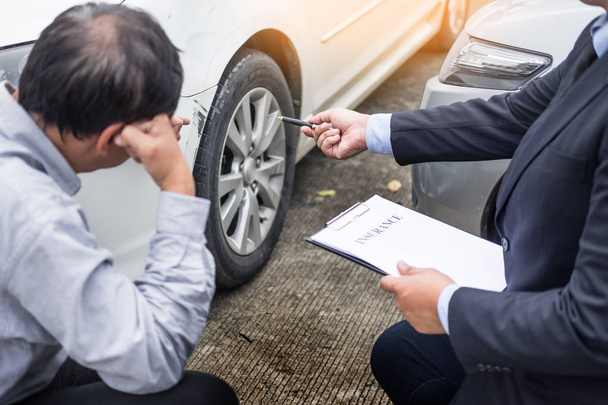 Agente de seguros que escribe en el portapapeles mientras examina el coche después de un
 - Foto, Imagen