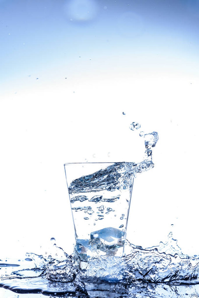 Jég, csepegtető, és fröccsenő tükörképe a pohárban a víz - Fotó, kép