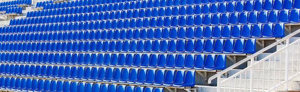 Sedie pieghevoli in plastica blu su una tribuna temporanea
. - Foto, immagini