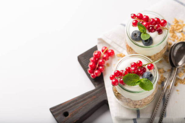 Breakfast with yogurt, granola and berries on white background. Healthy food concept. Healthy breakfast ingredient - Foto, imagen