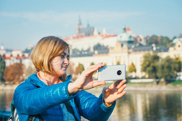 Woman taking a selfie in Prague, Prague Castle and Saint Vitus Cathedral in the background - Photo, Image