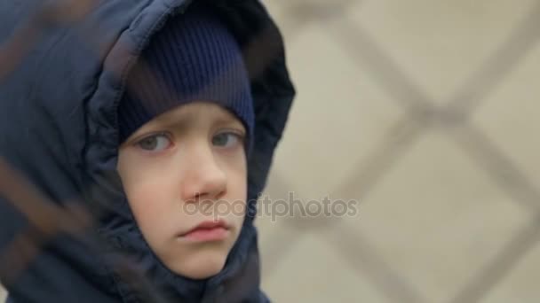 Мальчик смотрит в камеру через решетку. Портрет ребенка
 - Кадры, видео
