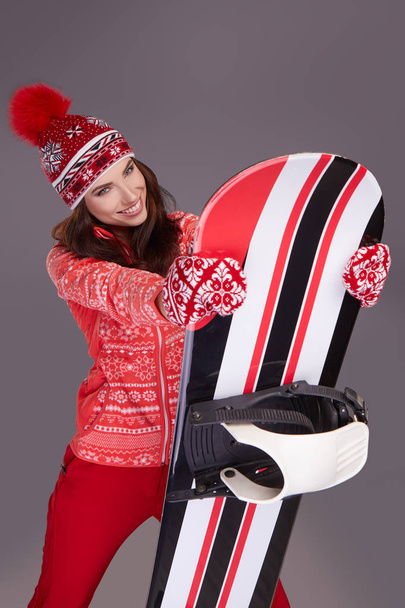 Woman wearing winter suit holding a snowboard in studio - Foto, Bild