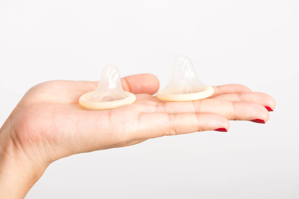 Aziatische vrouw hand met condooms op witte achtergrond - Foto, afbeelding