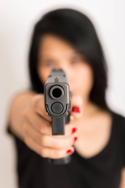 молода жінка азіатська дівчина тримає пістолет, спрямований на пістолет, з вибірковим фокусом
 - Фото, зображення