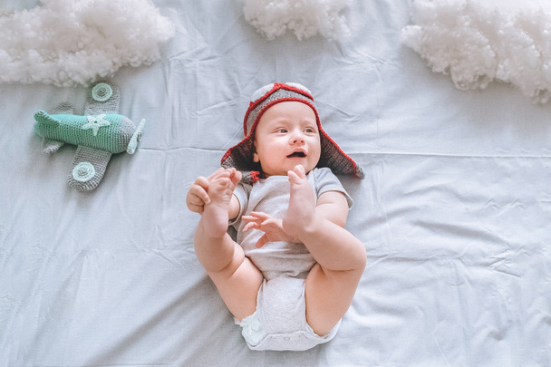 ベッドで綿製の雲に囲まれておもちゃの飛行機とパイロット帽子で夢のような幼児の平面図 - 写真・画像