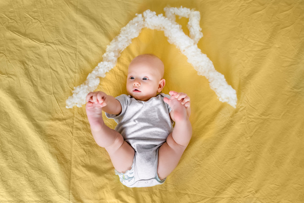 pohled shora kojenecké dítěte pod střechou domu, vyrobené z bavlny v posteli - Fotografie, Obrázek