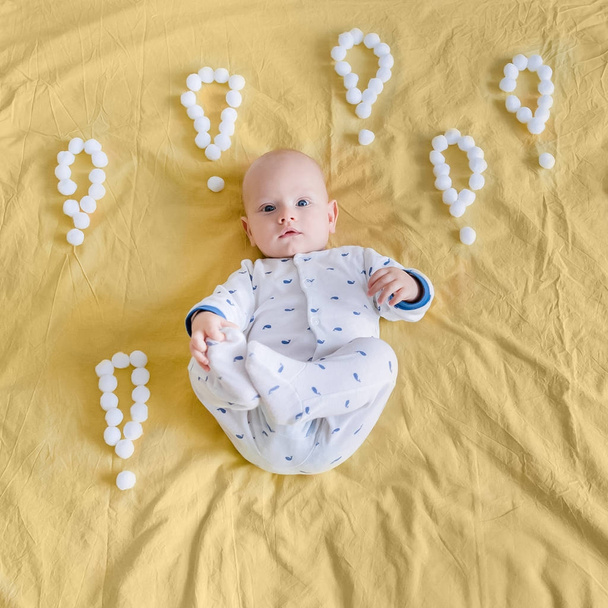 vue de dessus du nourrisson entouré de points d'exclamation faits de boules de coton au lit
 - Photo, image