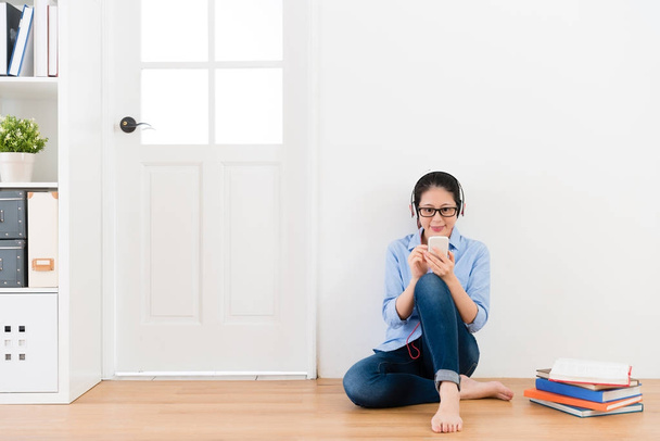 young lady wearing headset sitting on wooden floor - Foto, Imagen