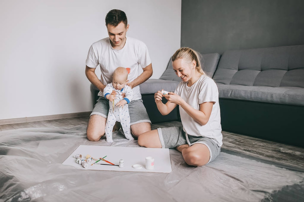 happy young family with little infant child painting together on floor at home   - Фото, зображення