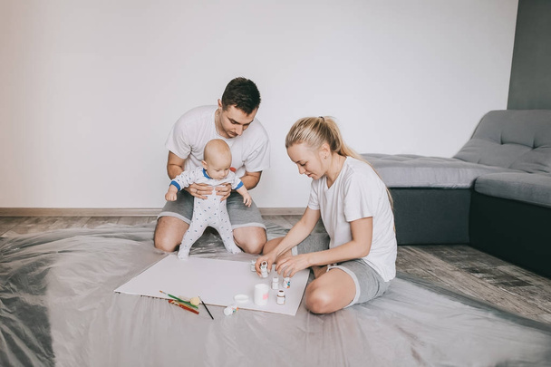 heureuse jeune famille avec beau petit enfant enfant peignant ensemble sur le sol à la maison
   - Photo, image
