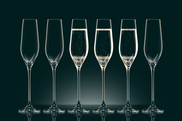 three transparent glasses with champagne and three empty glasses on black - Фото, зображення