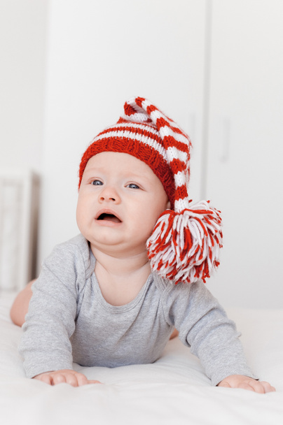 portrait of cute little infant child in knitted hat lying on bed - Фото, изображение